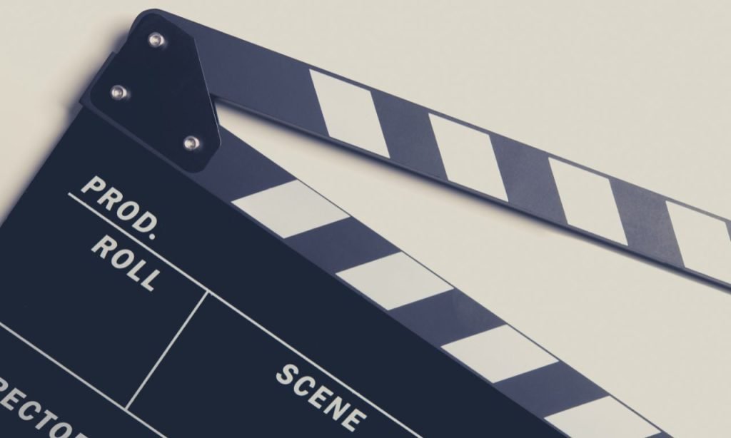 Historische Filmklappe und Filmrollen auf einer Holzfläche